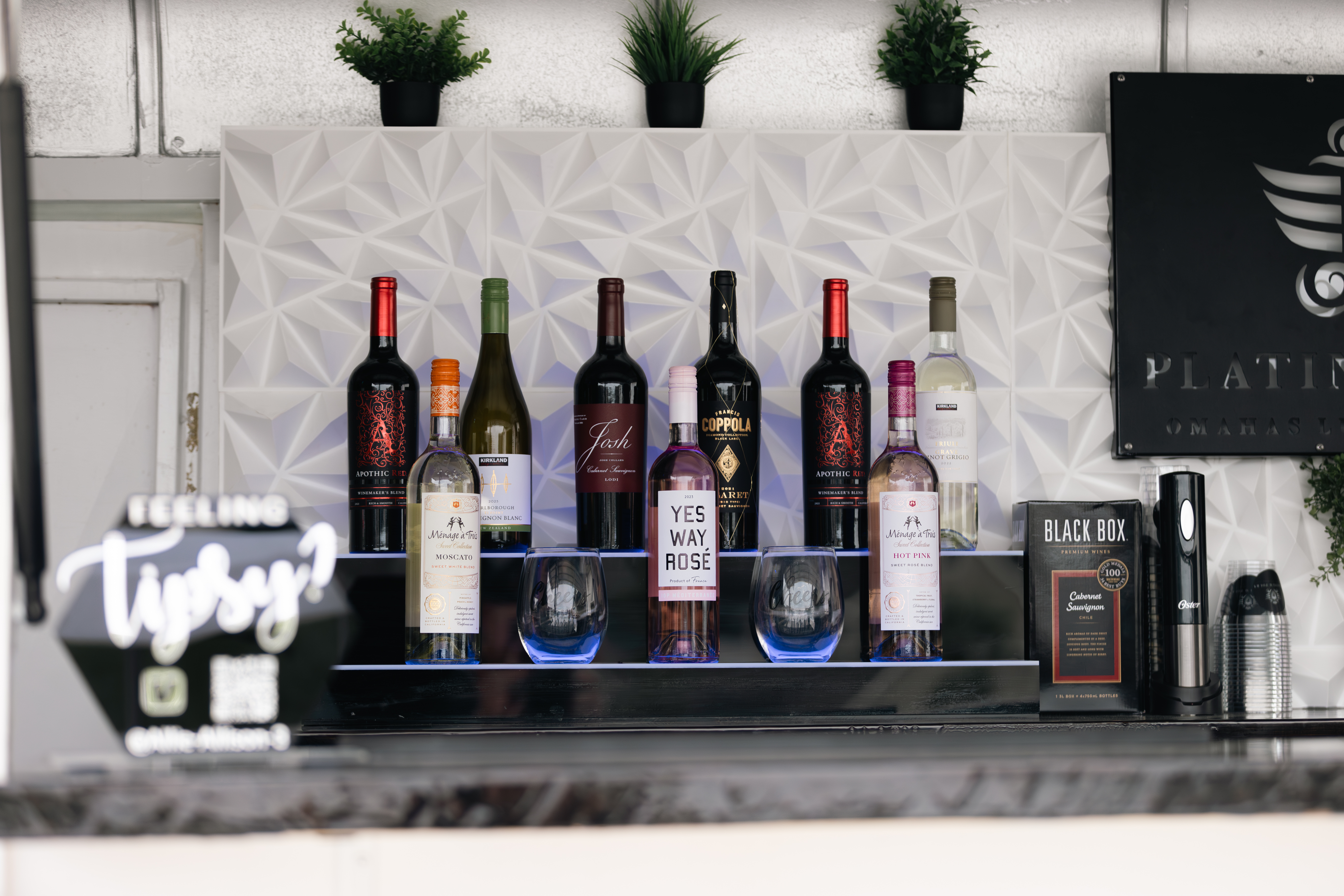 A premium selection of bar mixers and bottles displayed on Platinum Pours' 3D LED backsplash, ready to pour