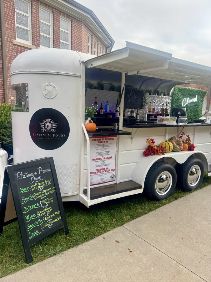 Platinum Pours' sleek black portable bar with the silver wing-crest logo at an indoor event