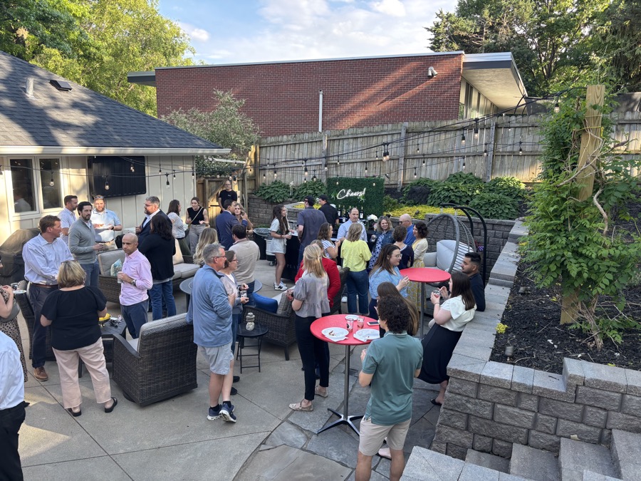 Backyard cocktail party with guests gathered around tall cocktail tables in golden hour light