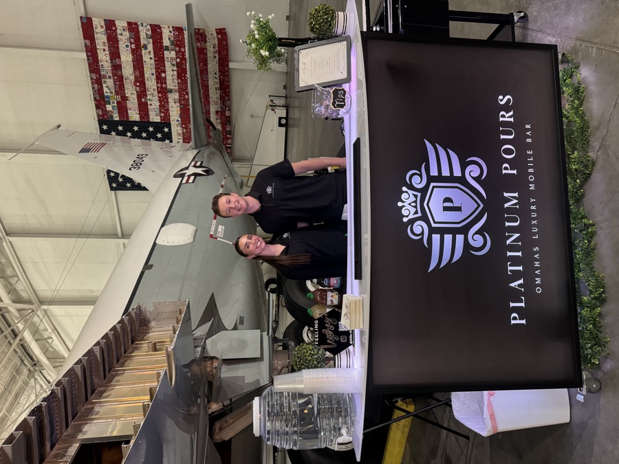 Platinum Pours bar set up in an aircraft hangar in front of a Navy jet for a special event