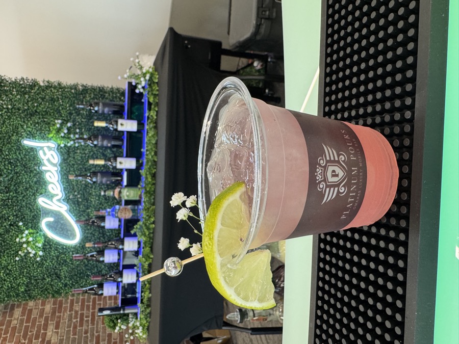 Frozen drink topped with a lemon wheel in a branded Platinum Pours cup in front of the Cheers wall