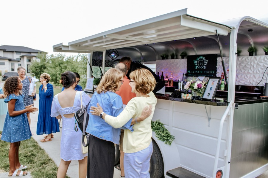 Guests in summer attire mingling at the Jackpot bar for an outdoor reception