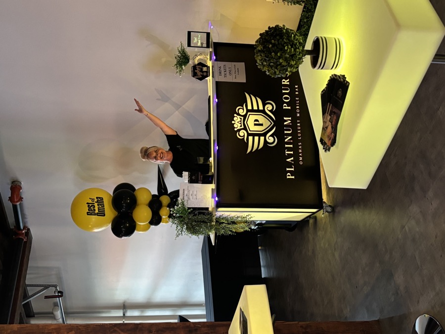 Platinum Pours setup at an awards celebration with bright yellow balloon arrangement and Best of Omaha branding