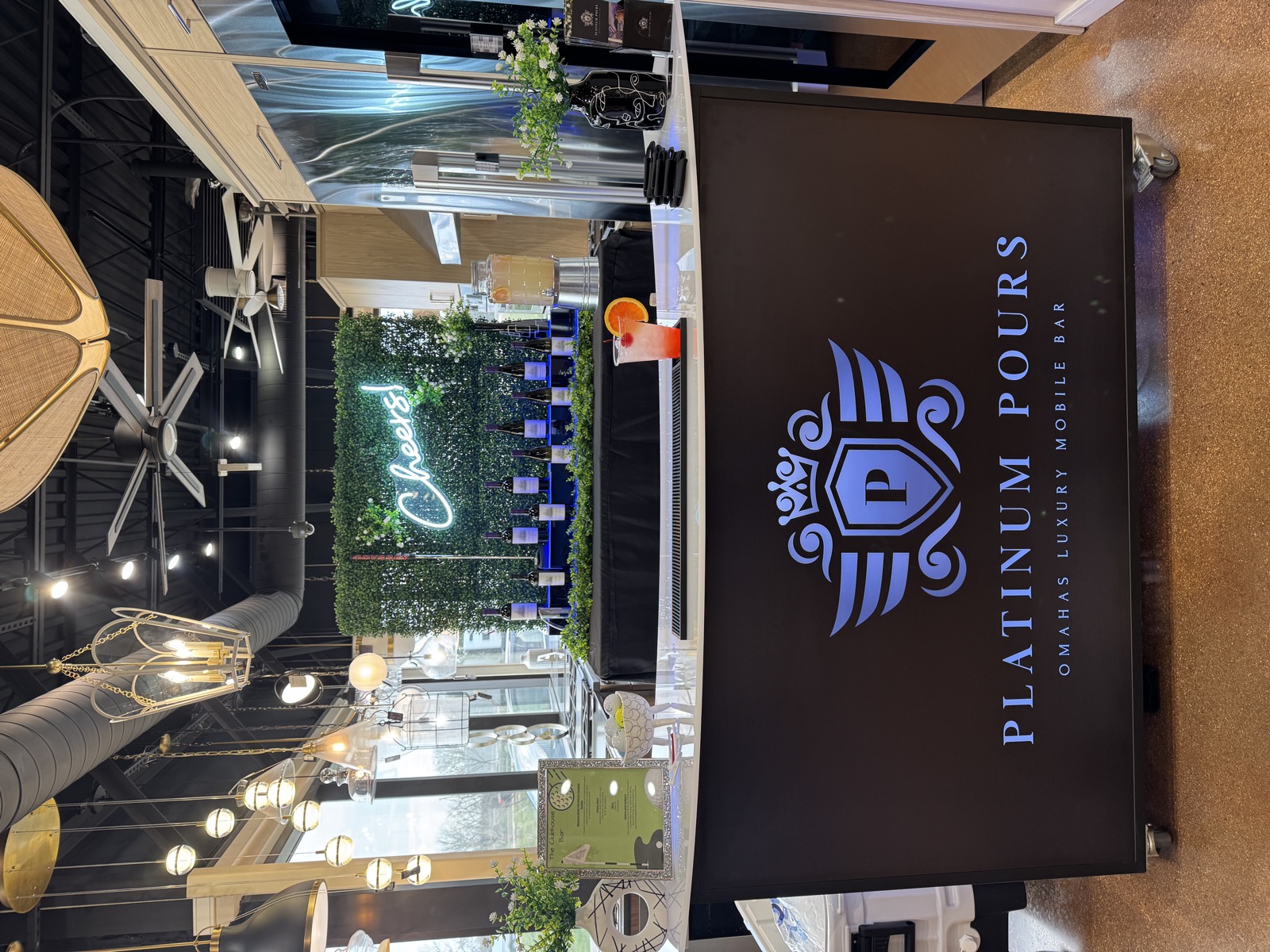 Platinum Pours' 6 Foot LED bar with blue logo, Cheers neon backdrop and wine display